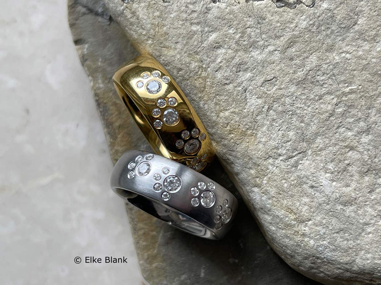 Zwei Pfotenringe in Silber und Gold mit Edelsteinen von oben fotografiert